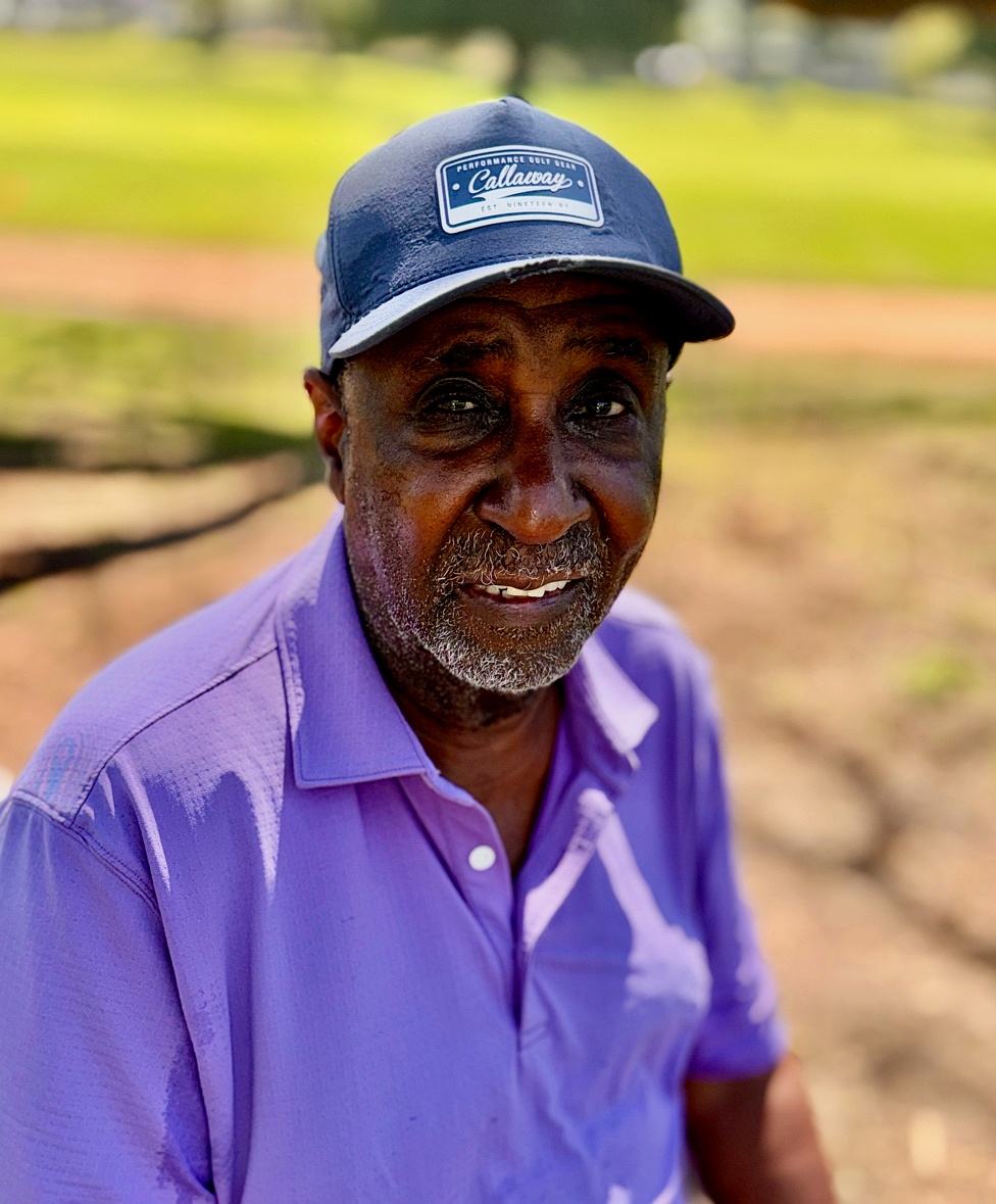 Jerome Green on the golf course, wearing a navy cap and lavender polo